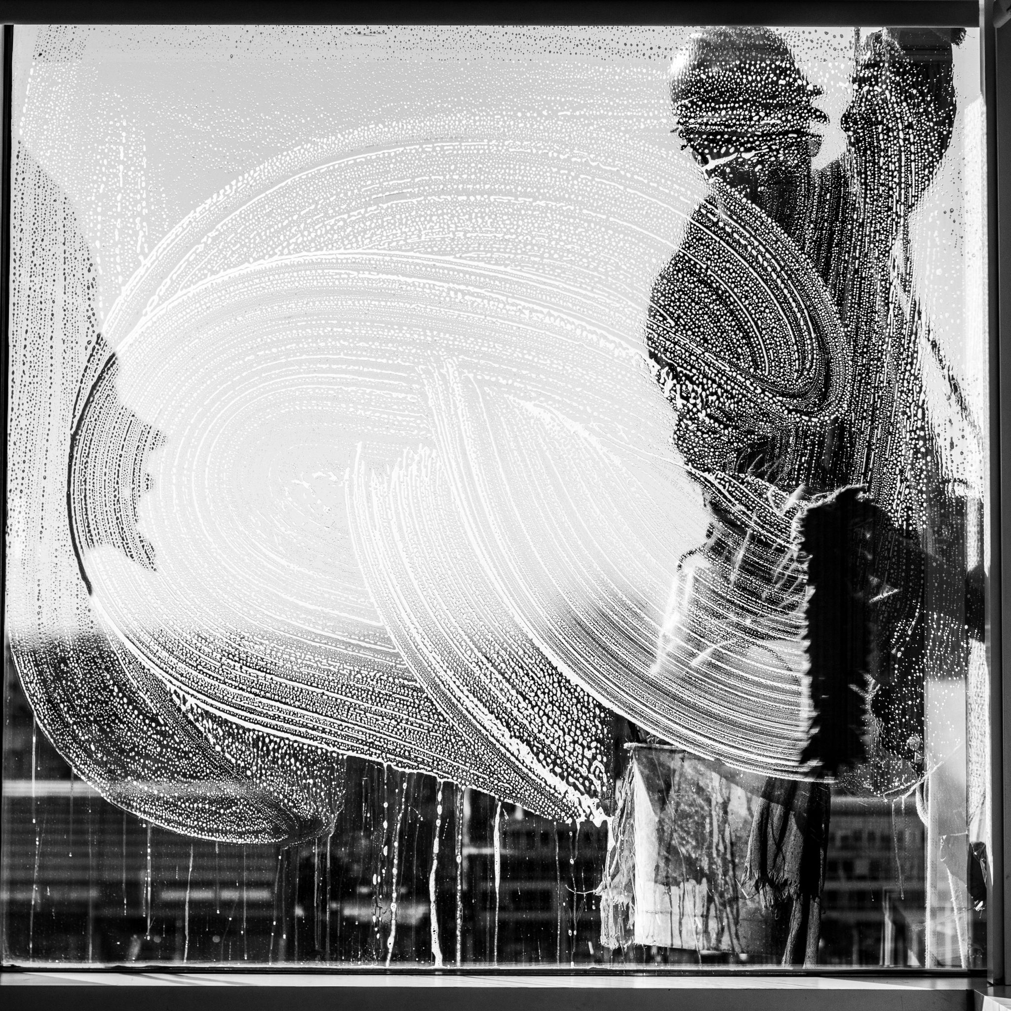 Black and white photo of a window cleaner with streaks on glass in Buenos Aires.
